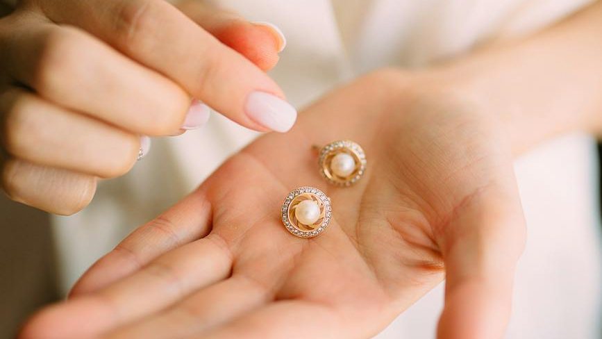 close up photo of person holding earrings